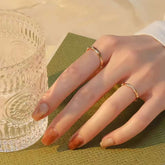 Hand holding ribbed glass, showing stackable bamboo gold rings in sunset light